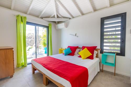 a bedroom with a large bed with colorful pillows at Iguane House Villas & Micro Spa in Sainte-Anne