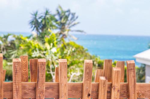 a wooden fence with the ocean in the background at Iguane House Villas & Micro Spa in Sainte-Anne