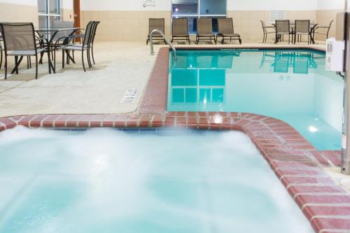 a swimming pool with tables and chairs in a building at Holiday Inn Express Hotel & Suites Alvarado by IHG in Alvarado