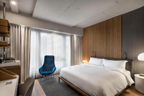 a hotel room with a bed and a blue chair at Hôtel Le Germain Montréal in Montréal