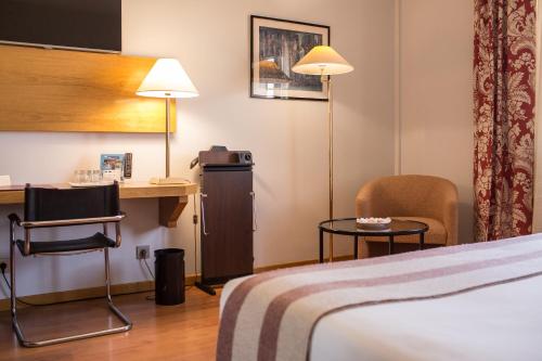 a hotel room with a bed and a desk and chairs at Hotel Vegas Altas in Don Benito