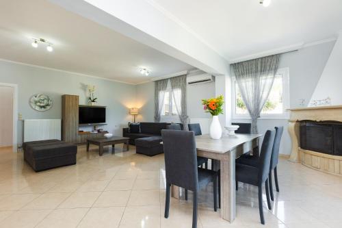 a dining room and living room with a table and chairs at Lilium Villa, summer aroma, By ThinkVilla in Perama
