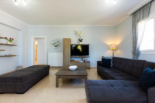 a living room with a couch and a tv at Lilium Villa, summer aroma, By ThinkVilla in Perama