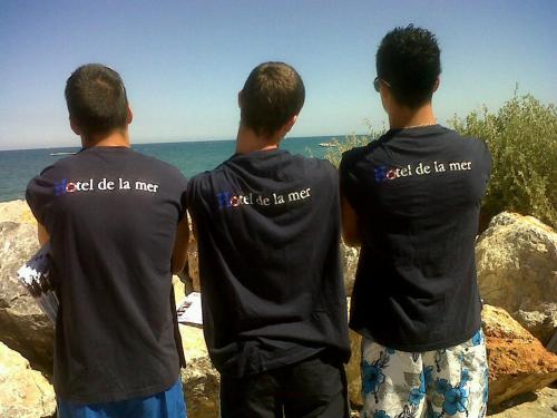 three men standing on rocks looking at the ocean at Hotel De La Mer in Le Barcarès