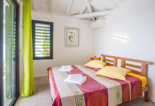 a bedroom with a bed with two towels on it at Iguane House Villas & Micro Spa in Sainte-Anne