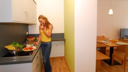 Una donna in piedi in una cucina che prepara il cibo di Hotel Residence NATURNSERHOF a Naturno
