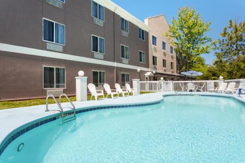 una piscina con sillas y un edificio en Holiday Inn Express Hotel & Suites Mebane, an IHG Hotel, en Mebane