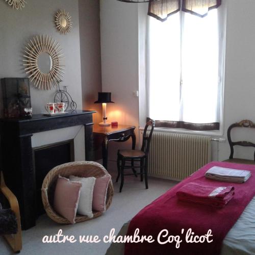 a bedroom with a bed with a fireplace and a chair at Le Coq en pâte in Romilly-sur-Seine