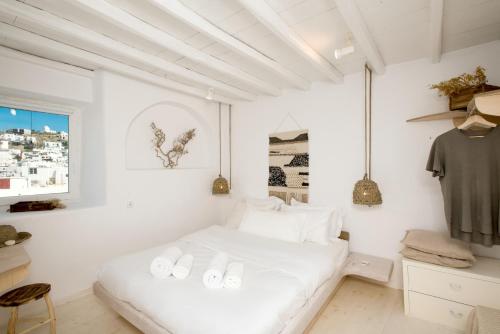 a white bedroom with a bed and a window at Villa Loom Mykonos Town in Mýkonos City