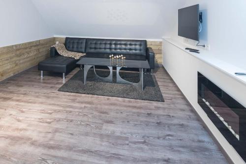 a living room with a couch and a table and a tv at Logies De blauwe regen in Beveren