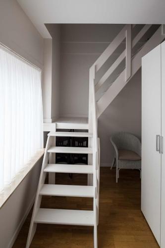 a white loft bed with wine bottles in a room at Logies De blauwe regen in Beveren