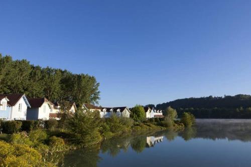 une rangée de maisons sur la rive d'une rivière dans l'établissement Appt HAMEAU DU LAC (apt 142) avec piscine et vue sur le lac, à Marciac