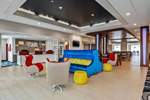 オーランドにあるHoliday Inn Express & Suites Orlando- Lake Buena Vista, an IHG Hotelのロビー(青いソファ、カラフルな椅子付)