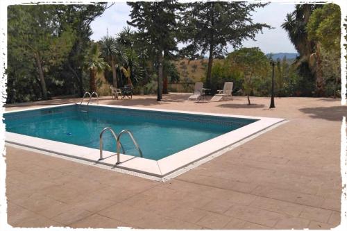 una piscina in un cortile accanto a una casa di Cortijo Casas Viejas a Málaga