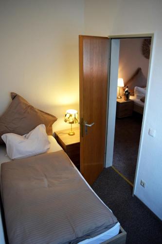 a bedroom with a bed and a door with a lamp at Hotel- Restaurant Kerzan´s in Dortmund