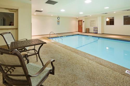 een groot zwembad met een tafel en stoelen ernaast bij Holiday Inn Express Hotel & Suites Freeport, an IHG Hotel in Freeport