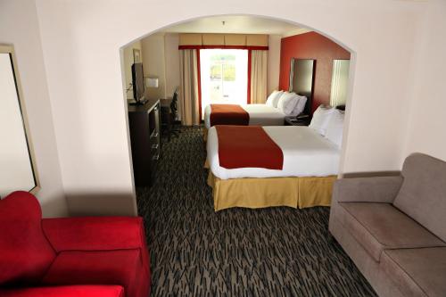 サムターにあるHoliday Inn Express Hotel & Suites - Sumter, an IHG Hotelのベッド2台とソファが備わるホテルルームです。