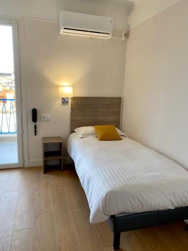 a bedroom with a large bed and a window at Hotel Courbet in Juan-les-Pins