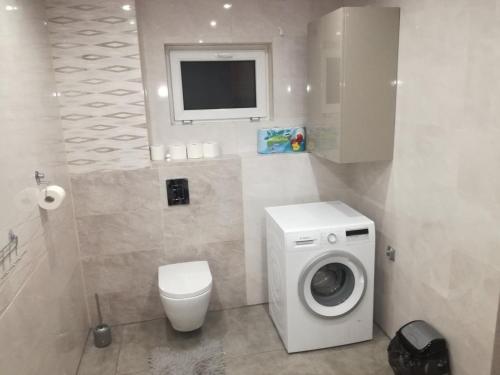a bathroom with a washing machine and a tv at Apartament u Wioli in Okleśna