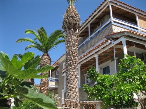 a building with two palm trees in front of it at Alex - Nancy Apartments - Zaga Beach in Koroni