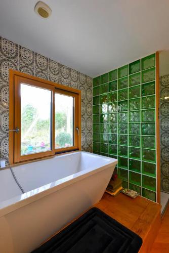La salle de bains est pourvue d'une baignoire et de carrelage vert. dans l'établissement Plage700m, Maison d'hôte très calme,écrin de verdure, Sauna, Borne élect, Bord GR34, à Moëlan-sur-Mer