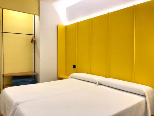 a room with two beds and a yellow wall at Albergue O Burgo in O Pedrouzo