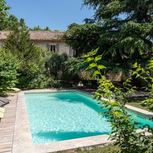 a swimming pool in the yard of a house at Hôtel Mas Vidau Porte des Alpilles in Saint-Étienne-du-Grès