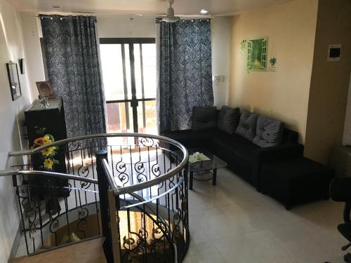 a living room with a black couch and a window at Maria's House nearby Victory Town Center in Kay Riapay