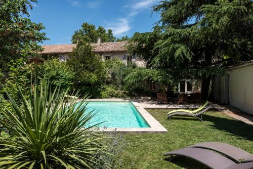 a swimming pool in the yard of a house at Hôtel Mas Vidau Porte des Alpilles in Saint-Étienne-du-Grès