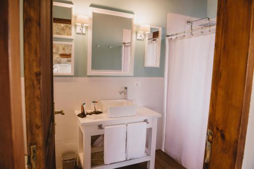 a white bathroom with a sink and a shower at El Legado Wine Lodge in Carmelo