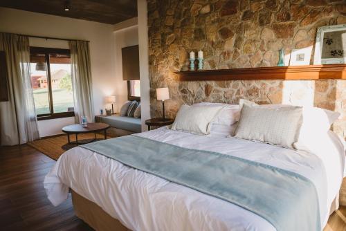 a bedroom with a large bed and a stone wall at El Legado Wine Lodge in Carmelo
