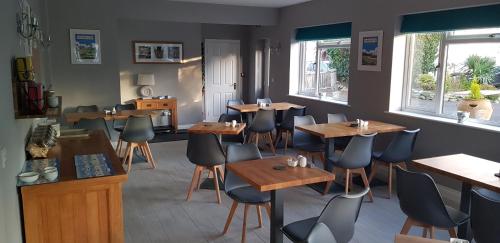 a restaurant with wooden tables and chairs and windows at Hensleigh House in Charmouth