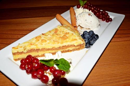 a plate of food with a piece of cake and fruit at Hotel- Restaurant Kerzan´s in Dortmund
