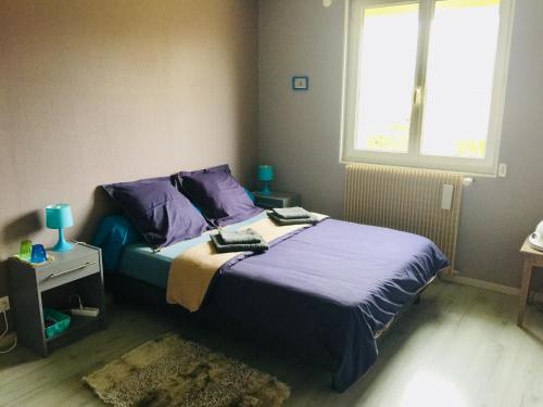 a bedroom with a bed with purple sheets and a window at Jolie halte normande in Balines