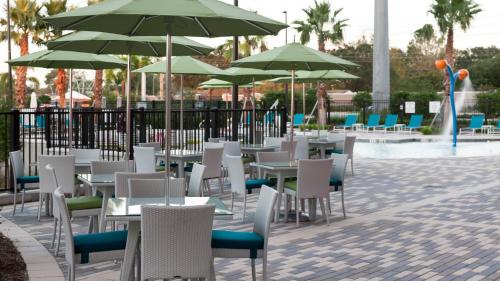 a group of tables and chairs with green umbrellas at Holiday Inn Express & Suites Orlando At SeaWorld by IHG - With Free Shuttle Service to SeaWorld Parks in Orlando