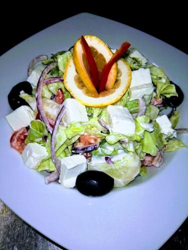 a salad with cheese and fruit on a white plate at Hotel Class in Oradea