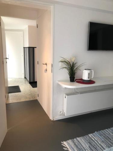 een woonkamer met een tv aan een witte muur bij Guesthouse Poppies in Oostende