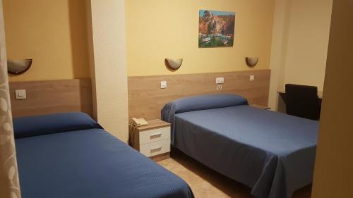 a hotel room with two beds and a desk at Hostal El Altet in El Altet