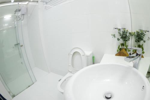 a white bathroom with a toilet and a shower at PERLA Dhangethi in Dhangethi