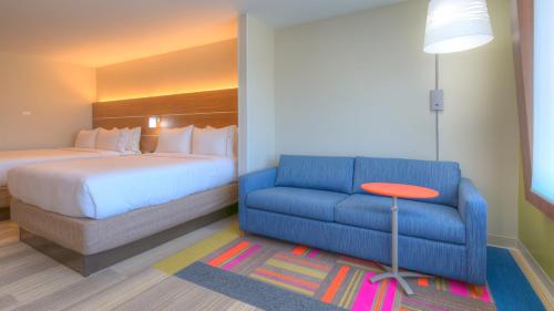 a hotel room with a bed and a blue couch at Holiday Inn Express & Suites Tulsa Midtown by IHG in Tulsa