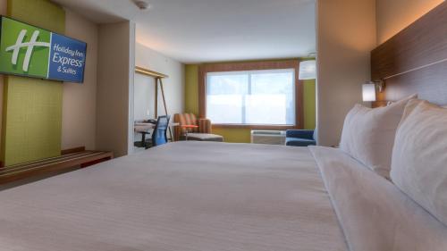 a hotel room with a large bed and a sign at Holiday Inn Express & Suites Tulsa Midtown by IHG in Tulsa