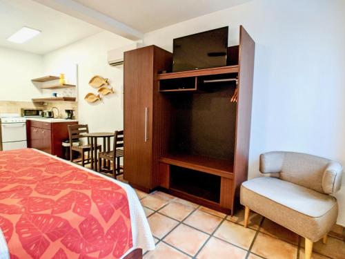 a bedroom with a bed and a chair and a kitchen at Sand Castle on the Beach - Adults Only in Frederiksted