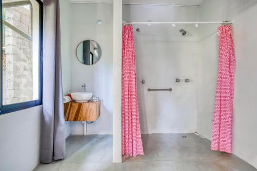 een badkamer met roze douchegordijnen en een wastafel bij Selina Santa Teresa South in Santa Teresa Beach