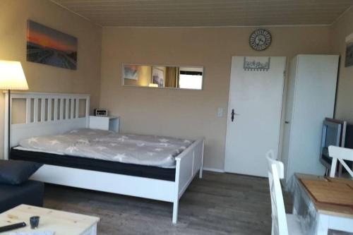 ein Schlafzimmer mit einem Bett und eine Tür mit einer Uhr an der Wand in der Unterkunft Dünennische Stranddistelweg in Fehmarn