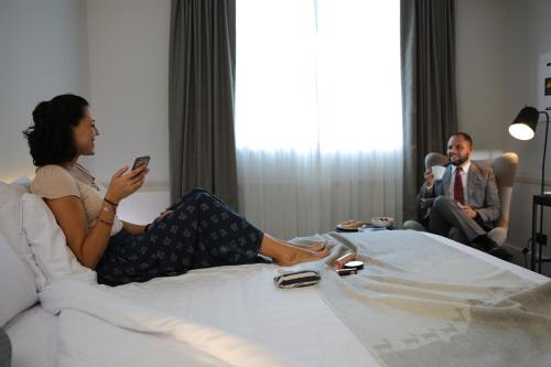 a woman laying on a bed looking at her cell phone at Casa Andina Premium San Isidro in Lima