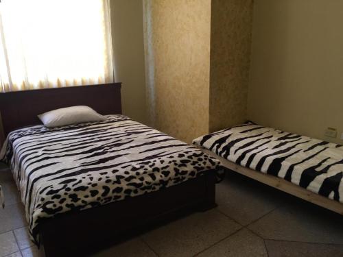 2 camas individuales en una habitación con ventana en Hotel de la Peña en Ambato
