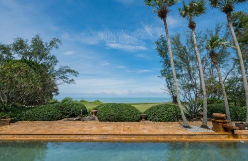 a swimming pool with palm trees and a view of the ocean at JW Marriott Phuket Resort and Spa in Mai Khao Beach