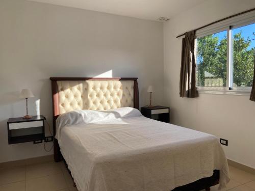 a bedroom with a bed with a white bedspread and a window at Mendoza Apartments Ezeiza Airport in Luis Guillón