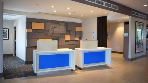 a lobby with two white tables and a blue wall at Holiday Inn Express & Suites - Jacksonville W - I295 and I10 by IHG in Jacksonville