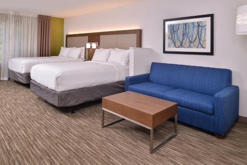 a hotel room with two beds and a blue couch at Holiday Inn Express & Suites Lacey - Olympia by IHG in Lacey